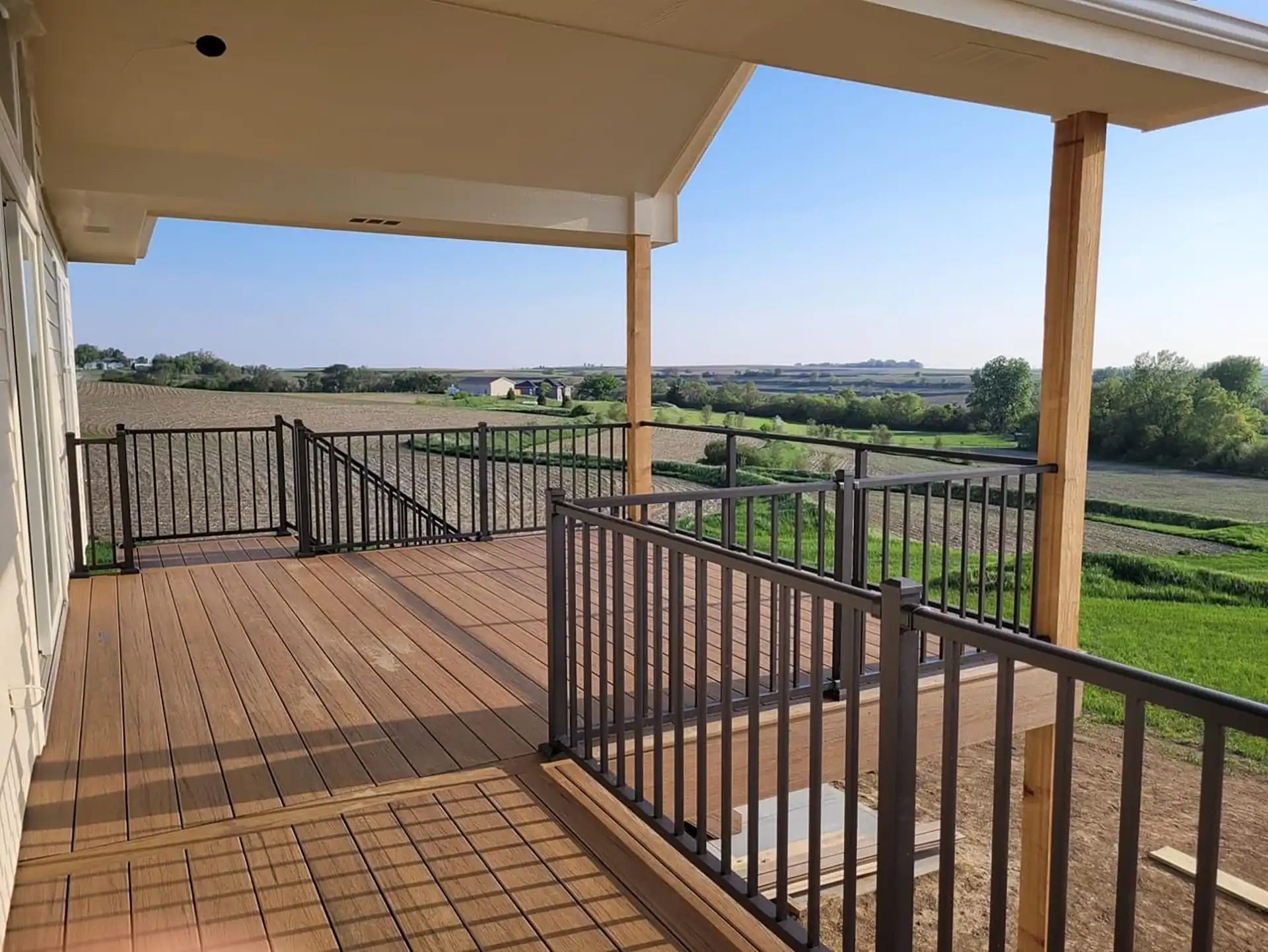 Photo of a covered deck with a fixed roof, metal railing, and steps