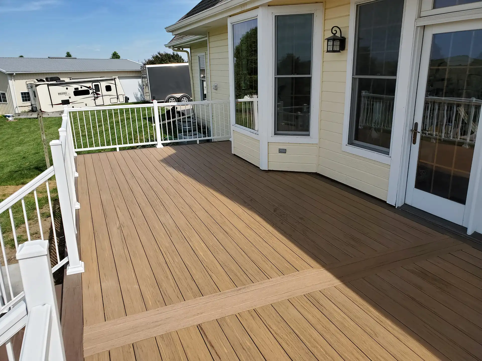 photo of a custom deck made with composite decking. Features deck railing and deck steps.