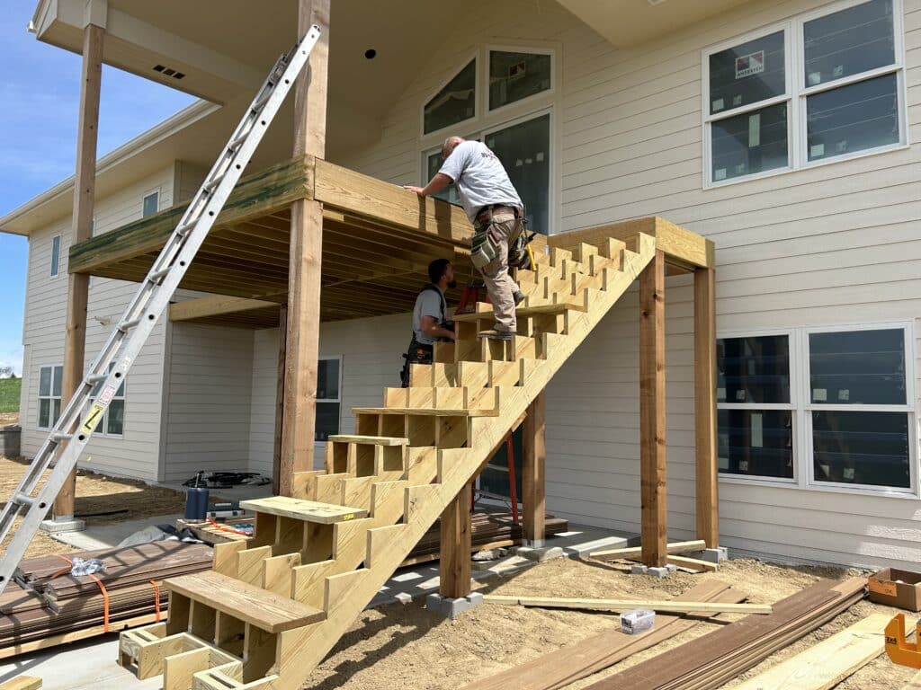 Photo of crews working on one of their large outdoor projects: An elevated deck with steps leading up