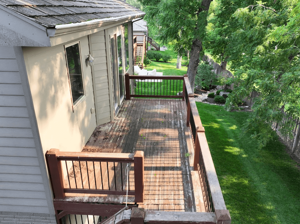 Photo of an elevated deck with worn-out wood deck boards and deck railing